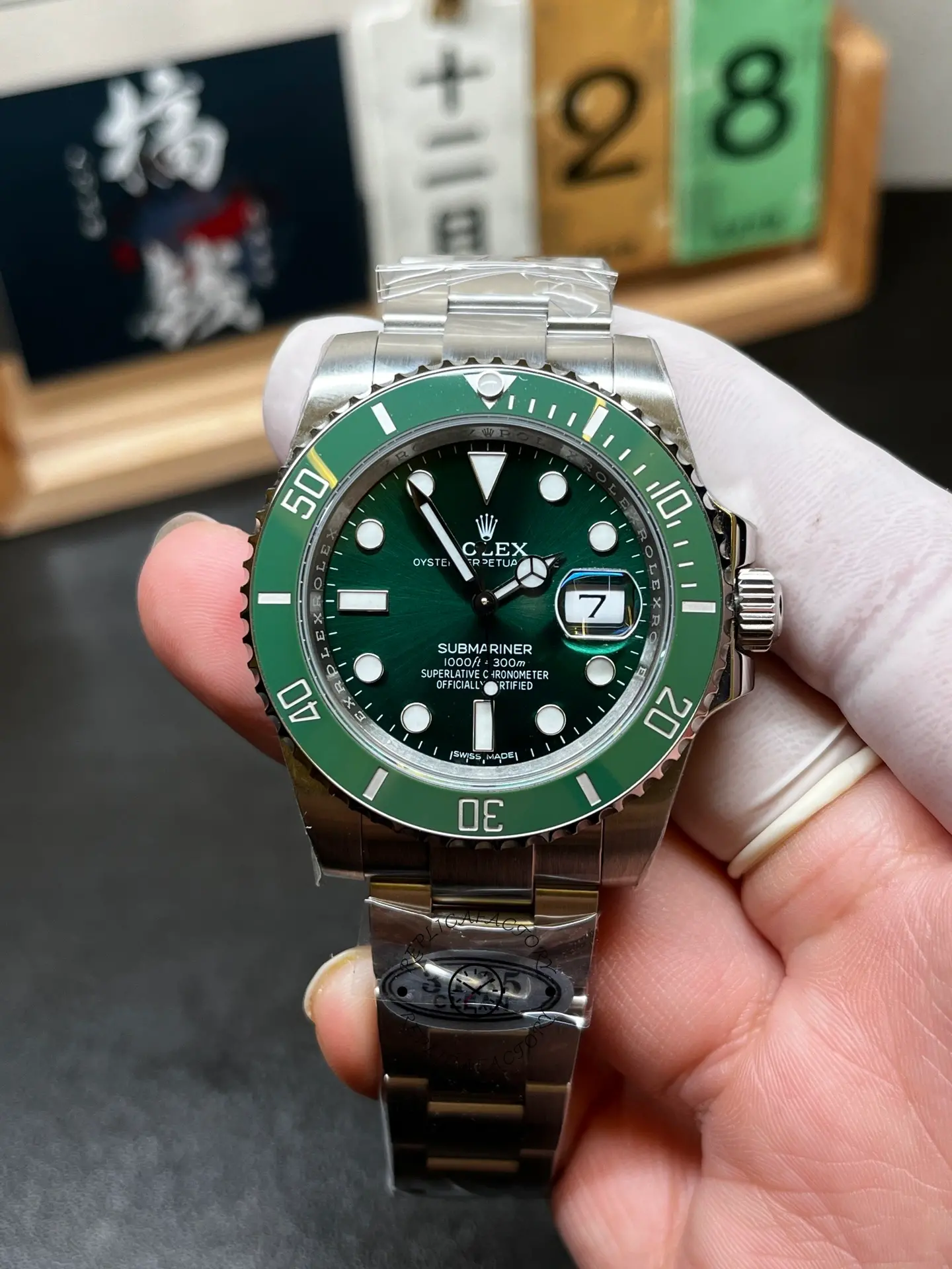 Front hand-held view of Rolex 116610LV Submariner Date with green dial, green bezel and Oyster bracelet.