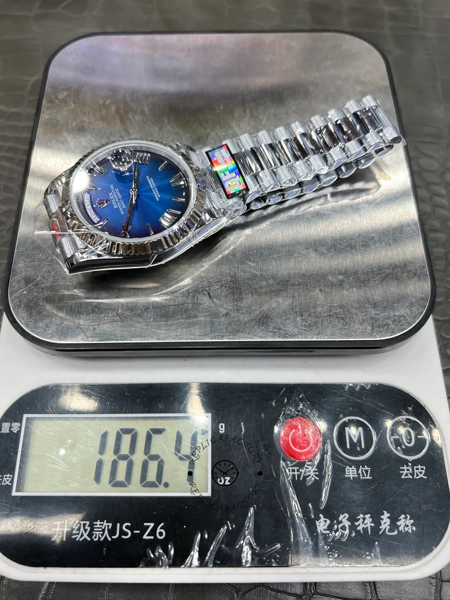 Weight display of Rolex Day-Date 228239-0076 placed on a digital scale showing approximately 186.4 grams.