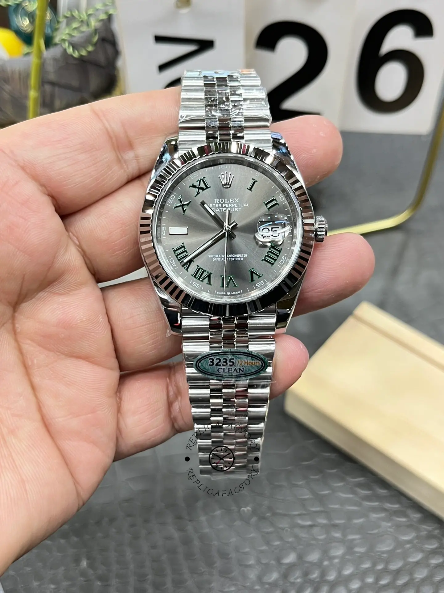 Handheld front view of Rolex Datejust 126334-0022 with slate grey dial and green Roman numerals.