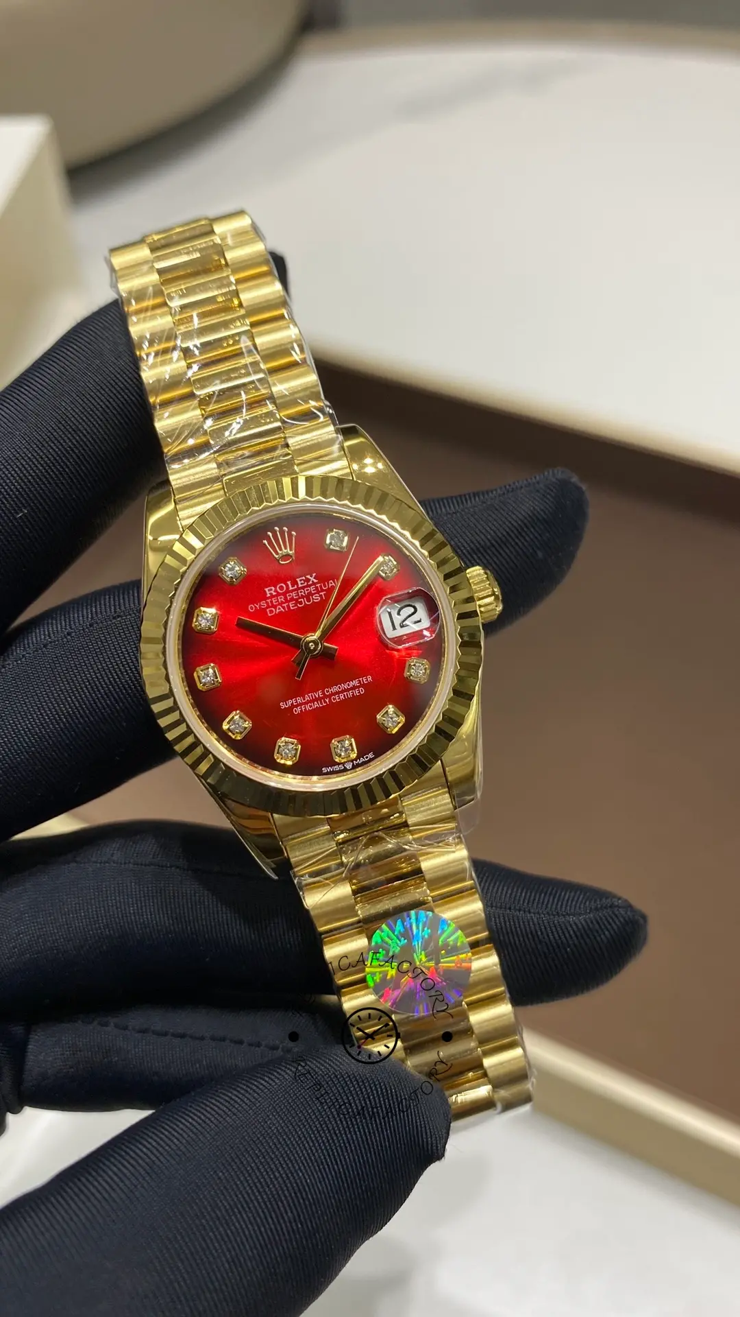 Rolex Datejust 278278-0049 held in hand, showing the red ombré dial, date magnifier and President bracelet.