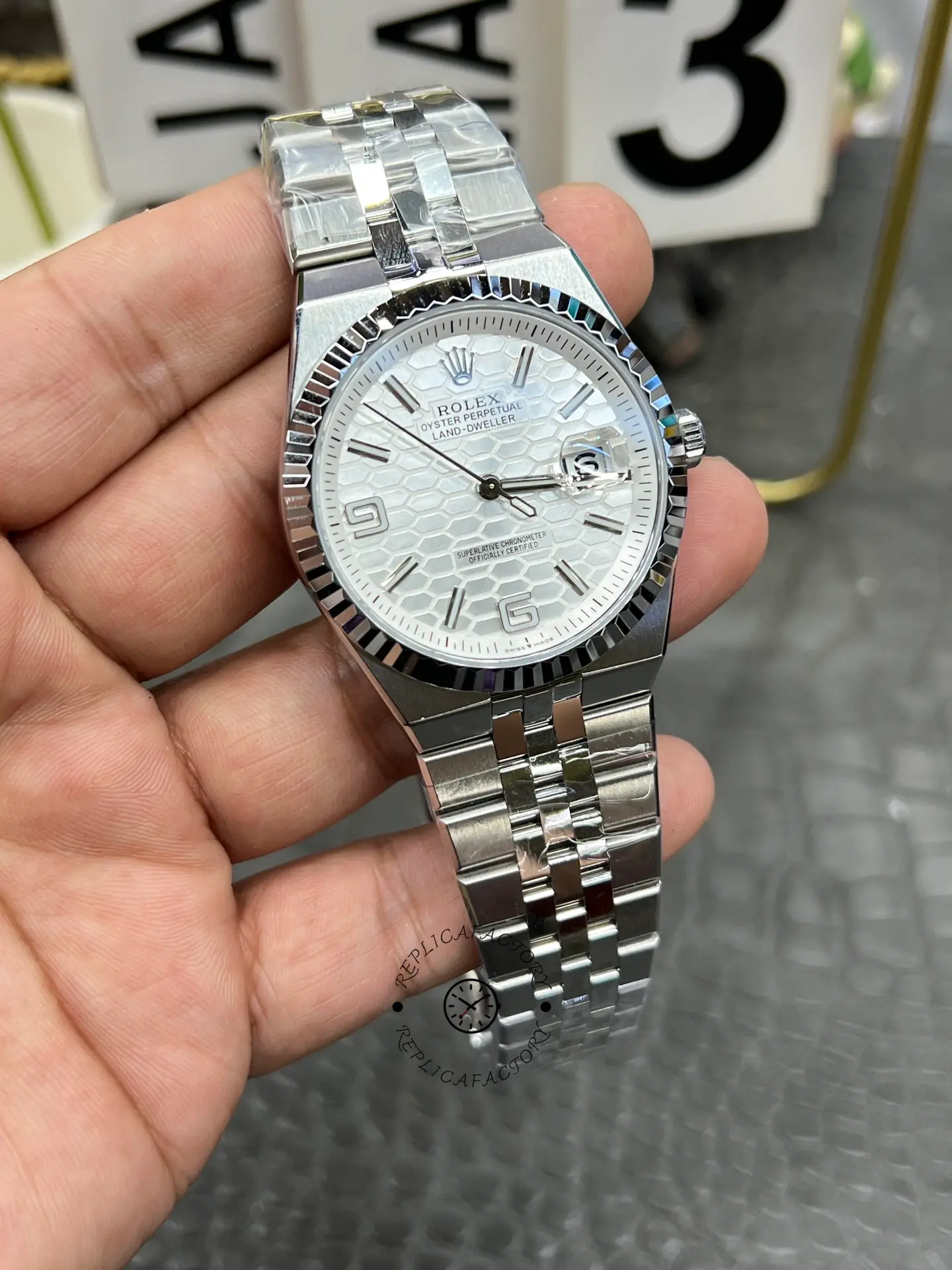 Front angle view of Rolex Land-Dweller 40 M127334-0001 replica with white dial, fluted bezel and flat bracelet.