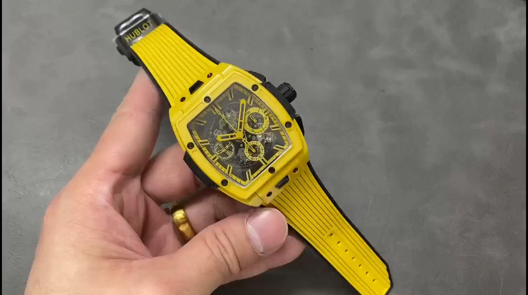Hand-held view of Hublot 642.CY.011Y.RX highlighting the yellow rubber strap and case profile. - Video