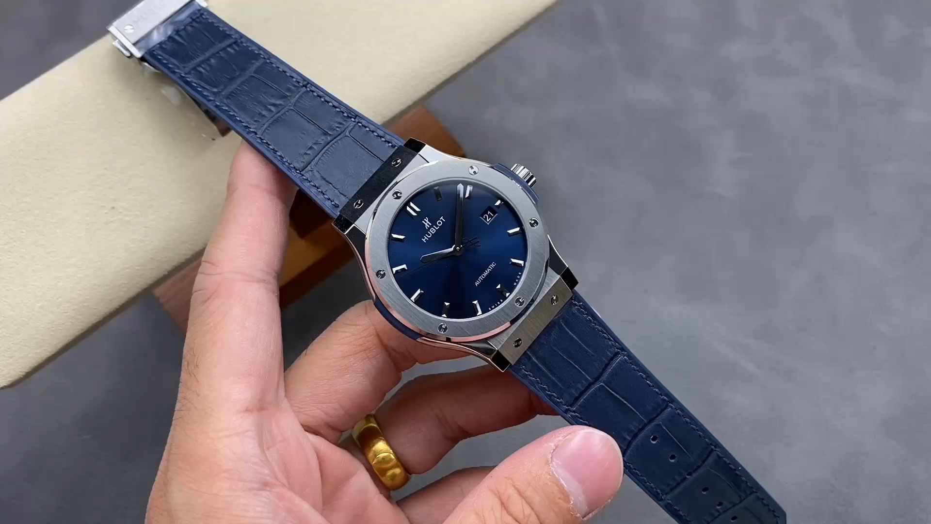 Strap in hand close-up of Hublot Classic Fusion 542.NX.7170.LR showing blue leather texture and stitching. - Video