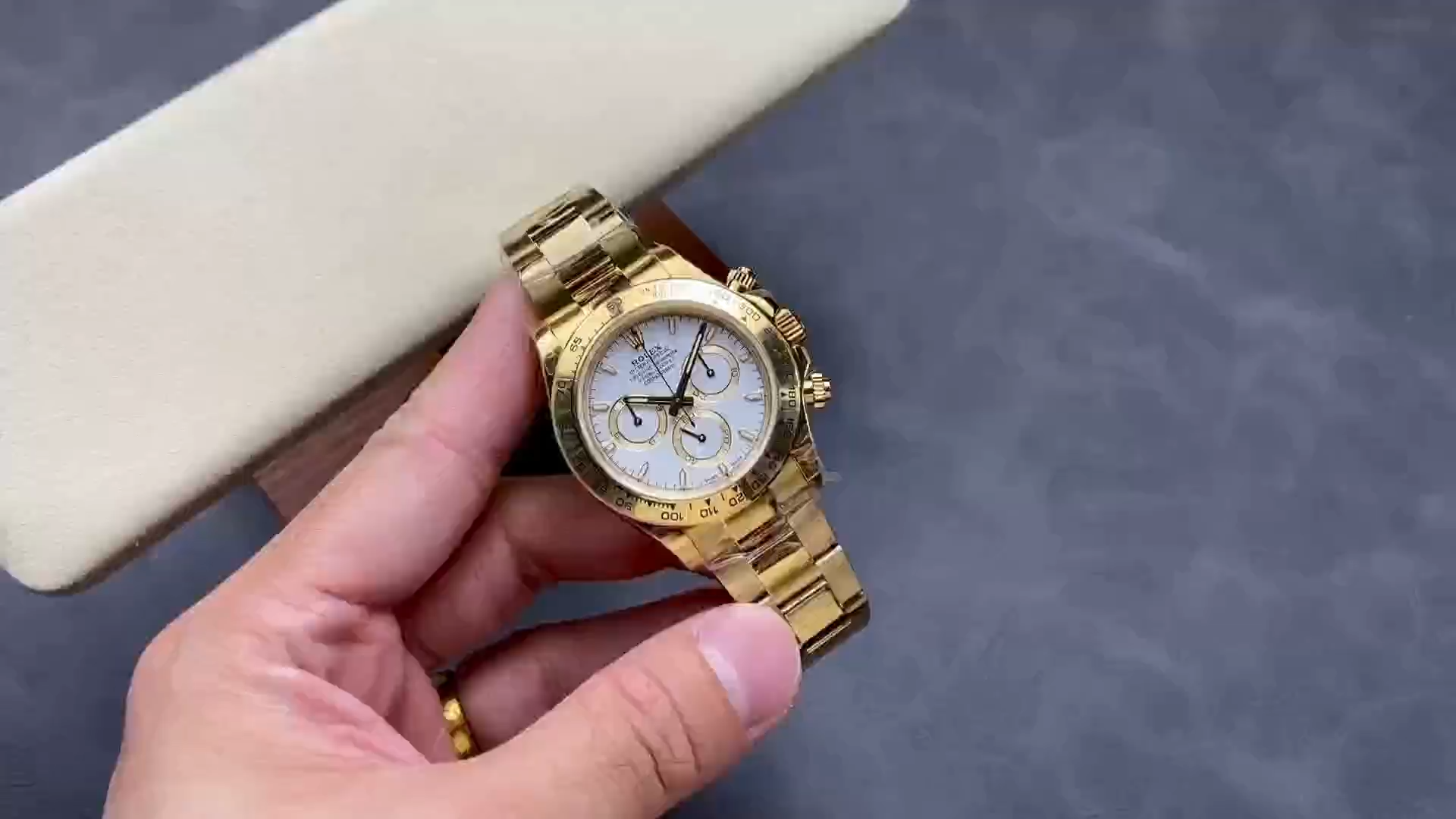 Video: hand holding Rolex Daytona 126508-0001, white dial and gold bracelet visible. - Video