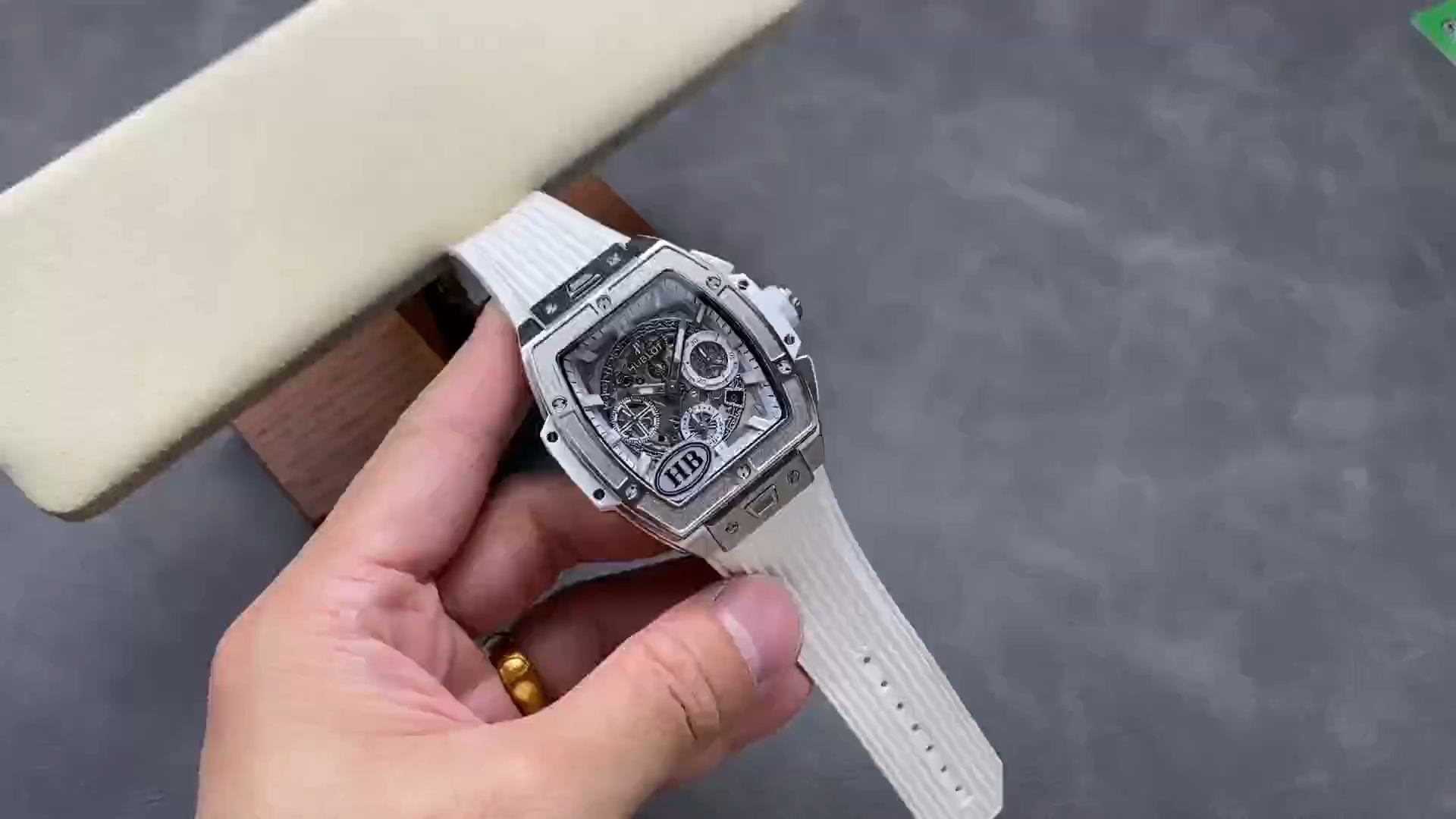 Video of Hublot 642.NE.2010.RW held in hand, showing the watch and white strap details. - Video