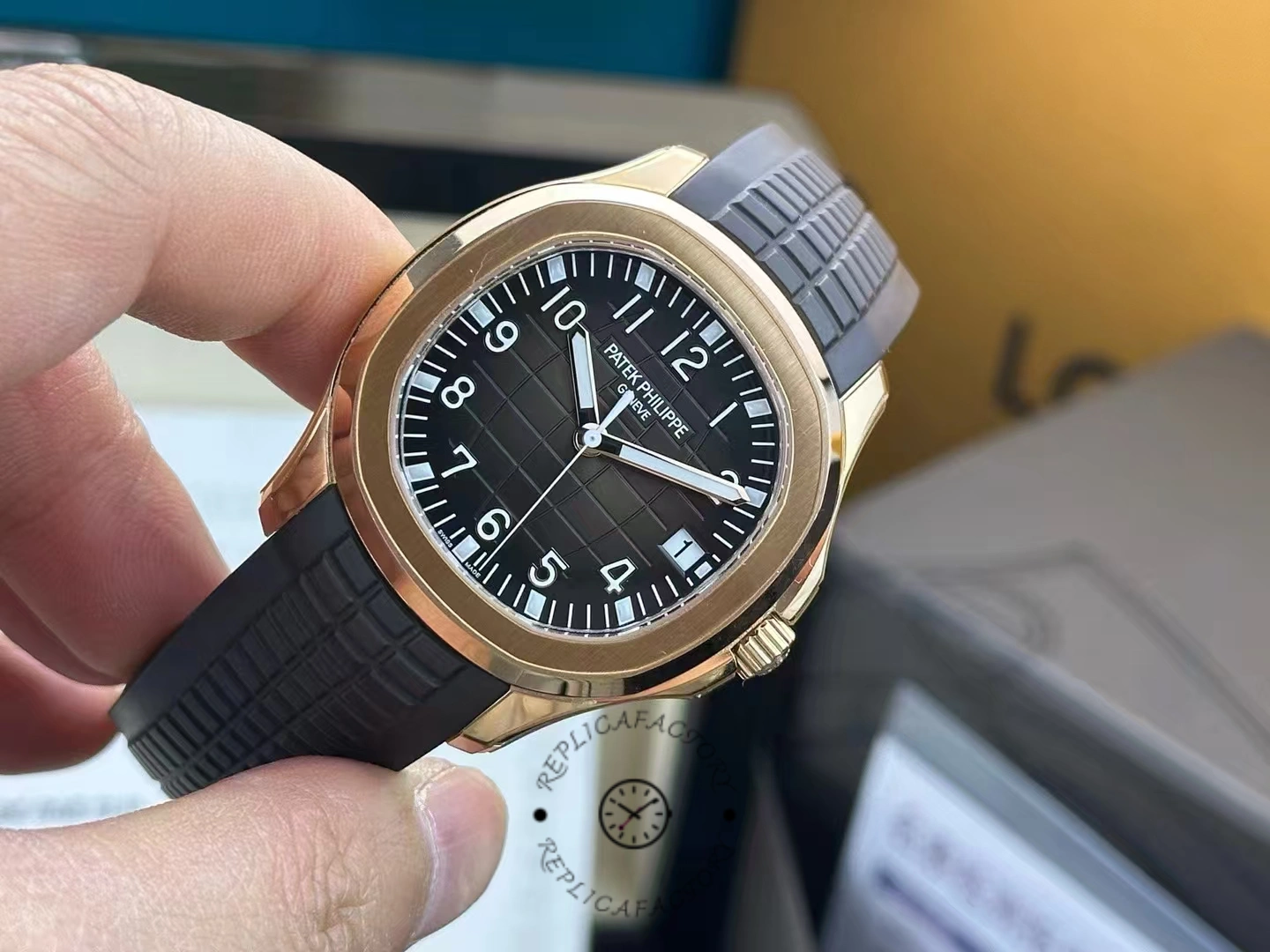 Close-up in hand of Patek Philippe Aquanaut 5167R-001 highlighting dial texture and luminous hands.