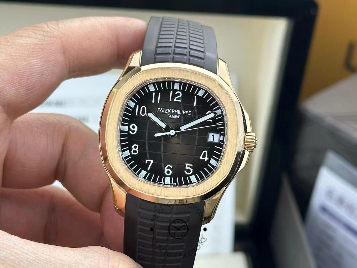 Hand-held Patek Philippe Aquanaut 5167R-001 showing rose-gold bezel shine and black rubber strap.