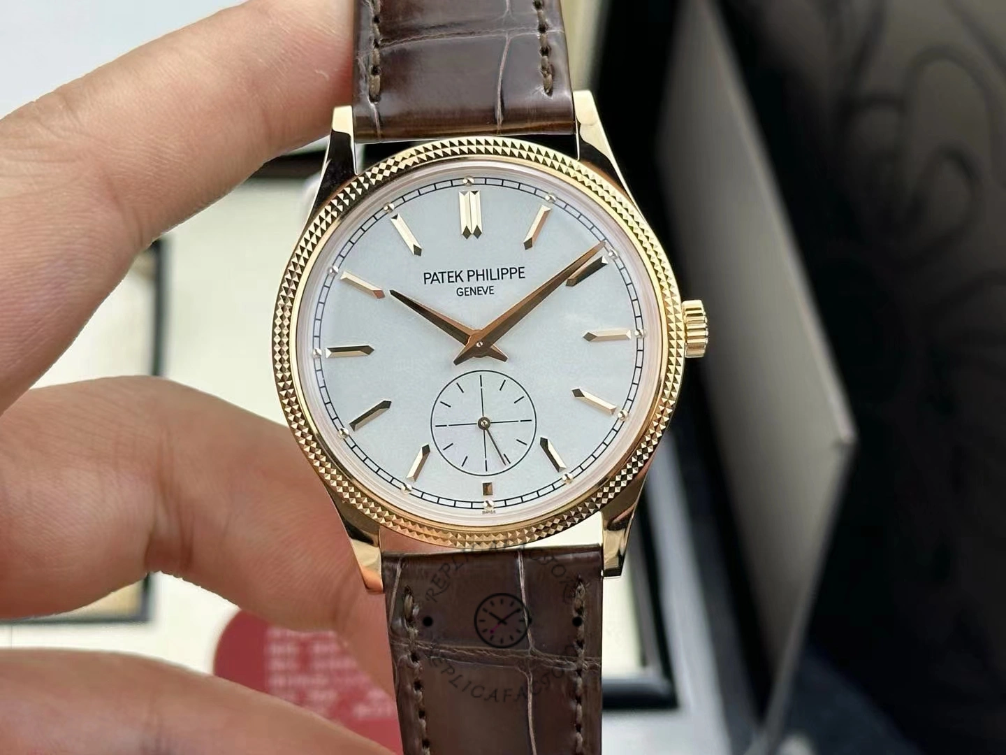 Hand-held close-up of Patek Philippe Calatrava 6119R-001 showing hobnail bezel and clean dial layout.