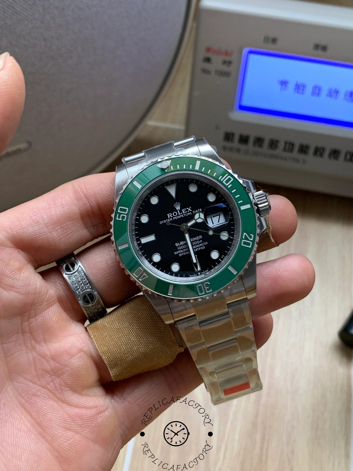Rolex Submariner 126610LV, close-up in hand with green bezel against a blue display background.