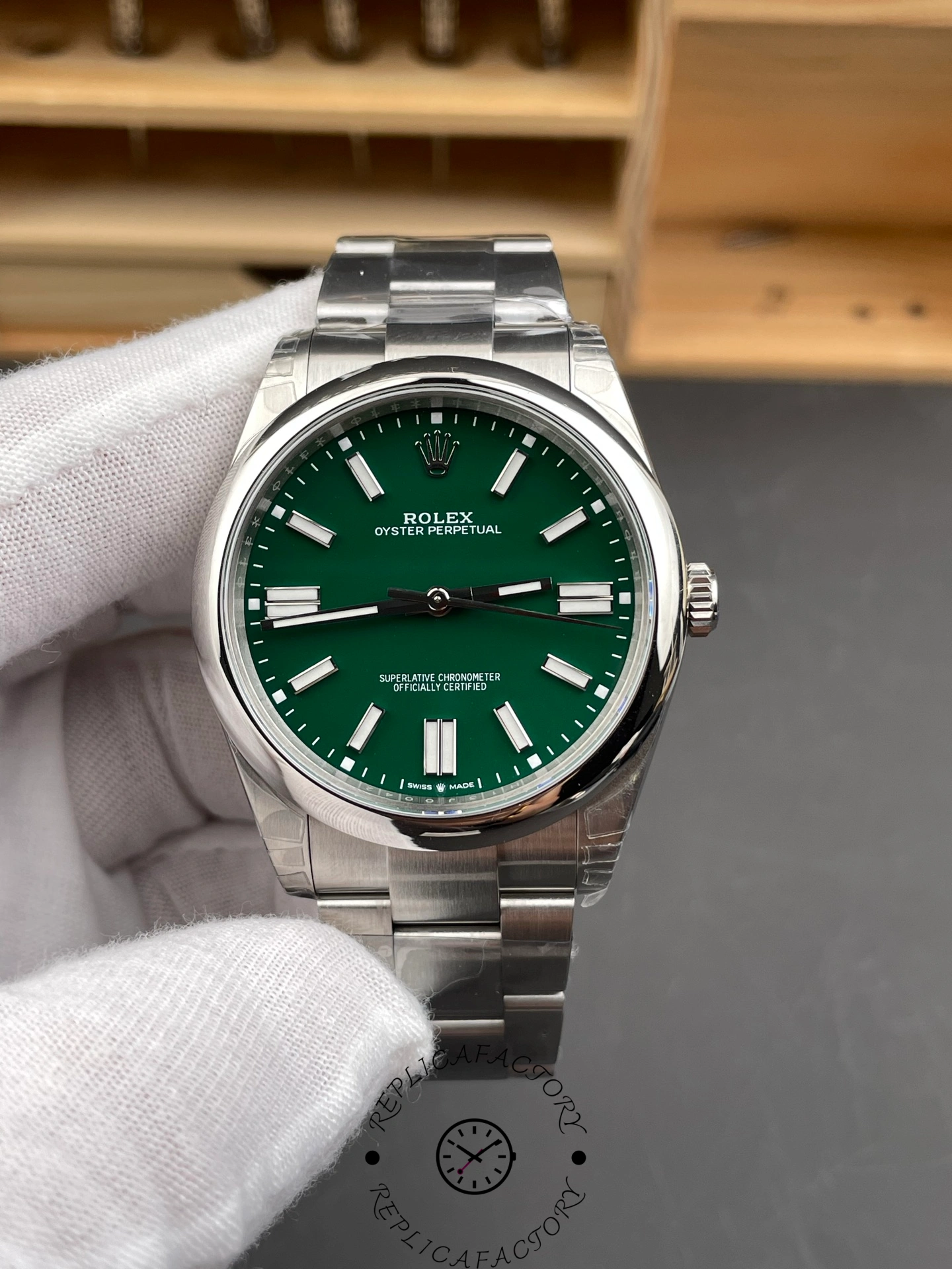 Gloved hand holding Rolex Oyster Perpetual 134300 0004, green dial, front view.