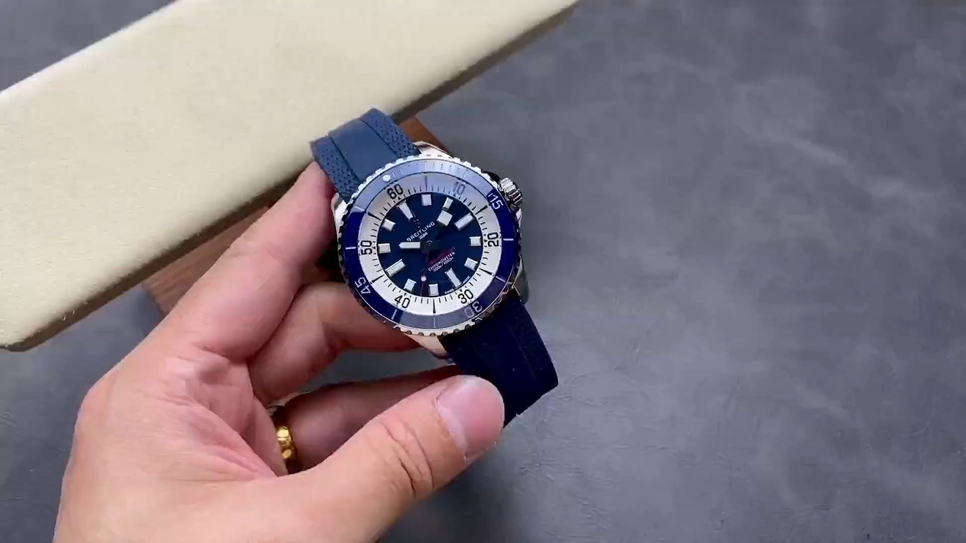 Video: hand-held Breitling Superocean A17375E71C1S1 showing blue rubber strap and bezel details. - Video