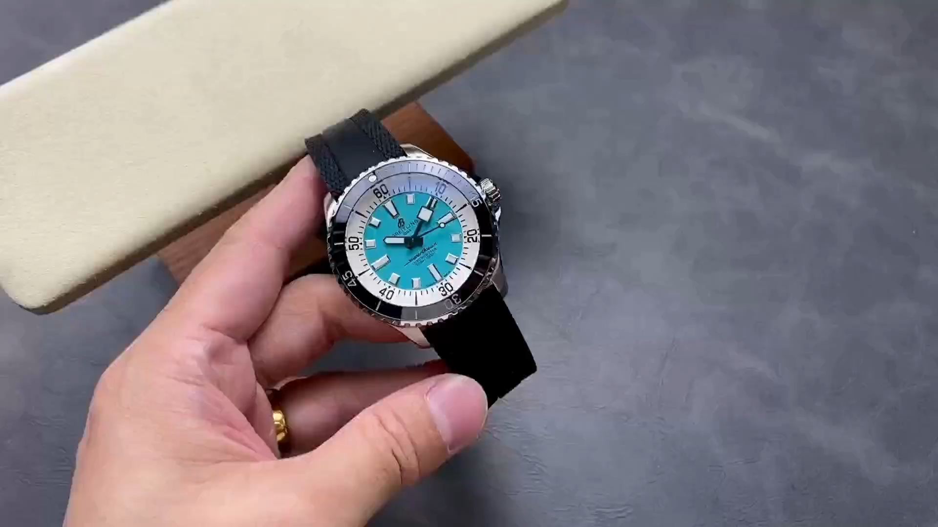 Video: hand-held Breitling Superocean Automatic A17376211L2S1 showing turquoise dial and black rubber strap. - Video