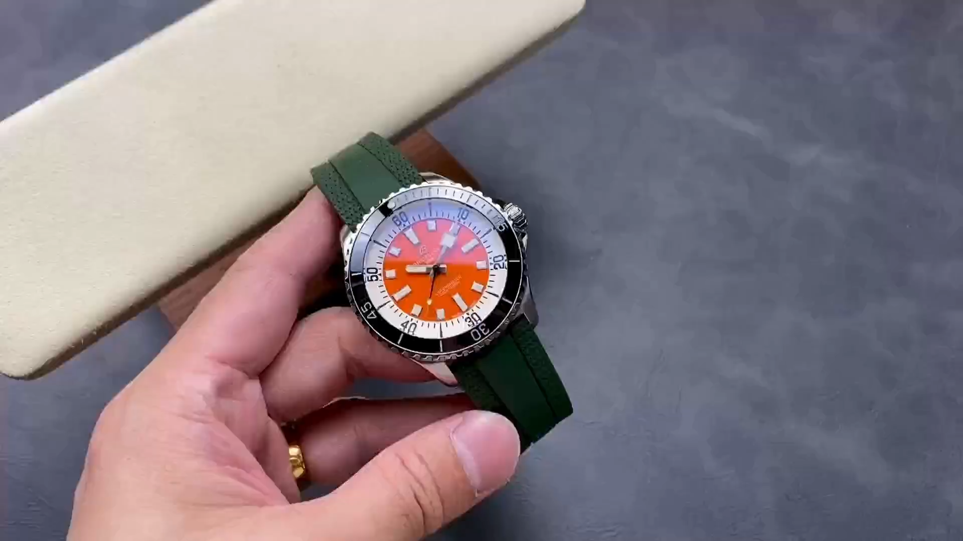 Video: hand-held Breitling Superocean Automatic A173751A1O1S1 showing orange dial and green rubber strap. - Video