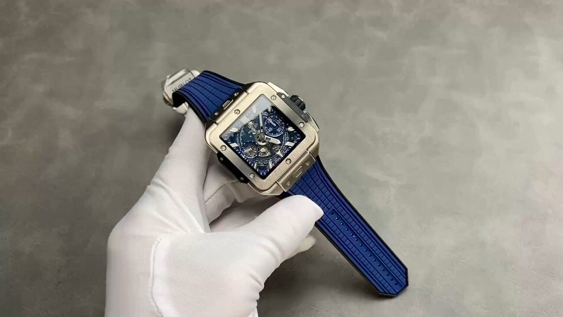 Handheld view of Hublot Square Bang Unico 821.NX.5170.RX showing the blue rubber strap laid out. - Video