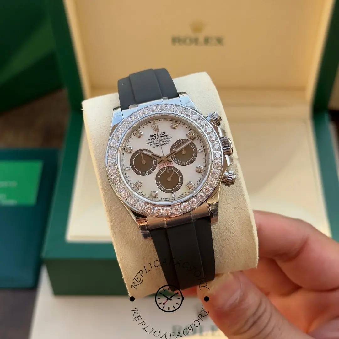 Hand-held view of Rolex Daytona 126589RBR in front of Rolex box, white dial and diamond bezel.