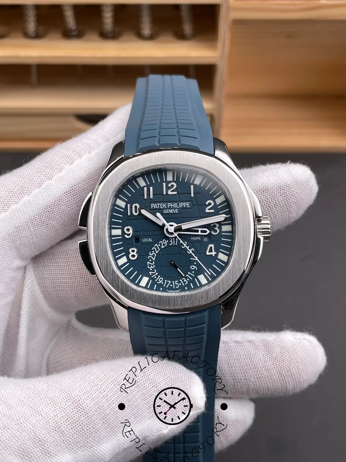 Hand-held Patek Philippe Aquanaut 5164G-001 showing blue dial, polished bezel, and tropical-style strap.