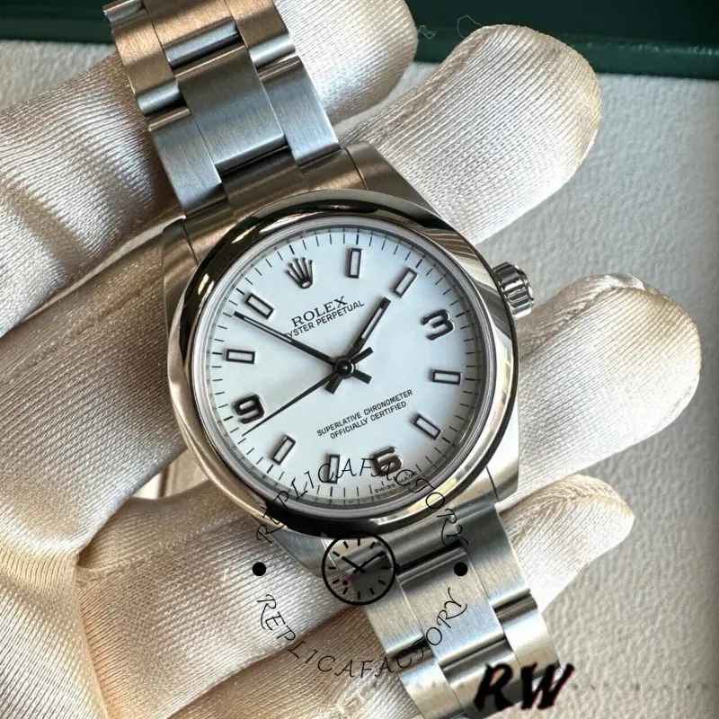 Glove-held close-up of the Rolex Oyster Perpetual 177200 showing white Arabic numerals and smooth bezel.