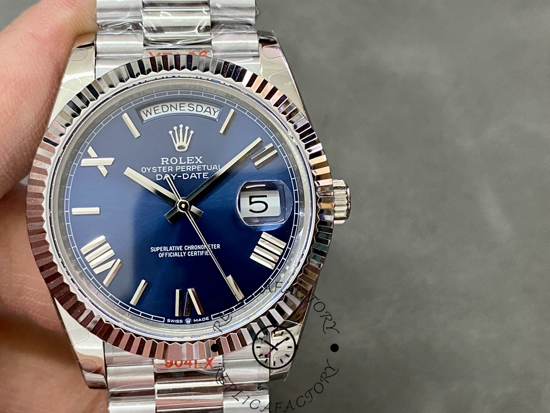 Close-up of Rolex Day-Date 228239 in hand showing blue dial, fluted bezel, day at 12 and date at 3.