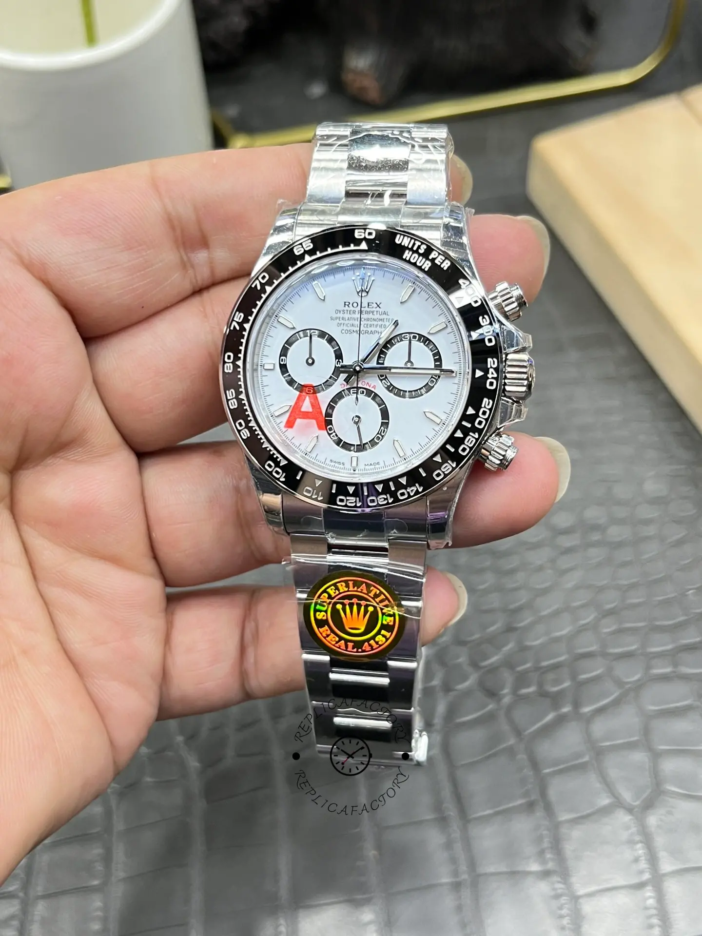 Rolex Daytona M126500LN-0001 handheld close-up, dial and bezel detail with protective stickers.